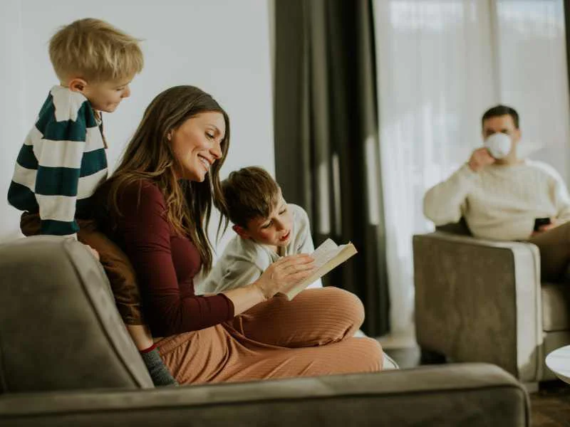 Padres e hijos compartiendo un momento de lectura y diálogo reflexivo en la sala de estar
