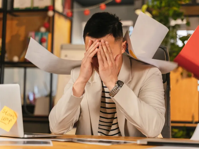 La vuelta al trabajo tras el verano puede afectar la salud emocional, según especialistas Trabajador en su escritorio con expresión reflexiva, simbolizando el impacto emocional del regreso laboral tras las vacaciones de verano