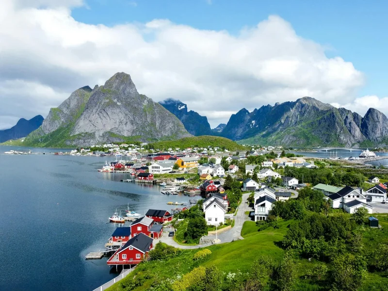 Paisaje veraniego de las Islas Lofoten en Noruega con cabanas rojas y montañas junto al mar