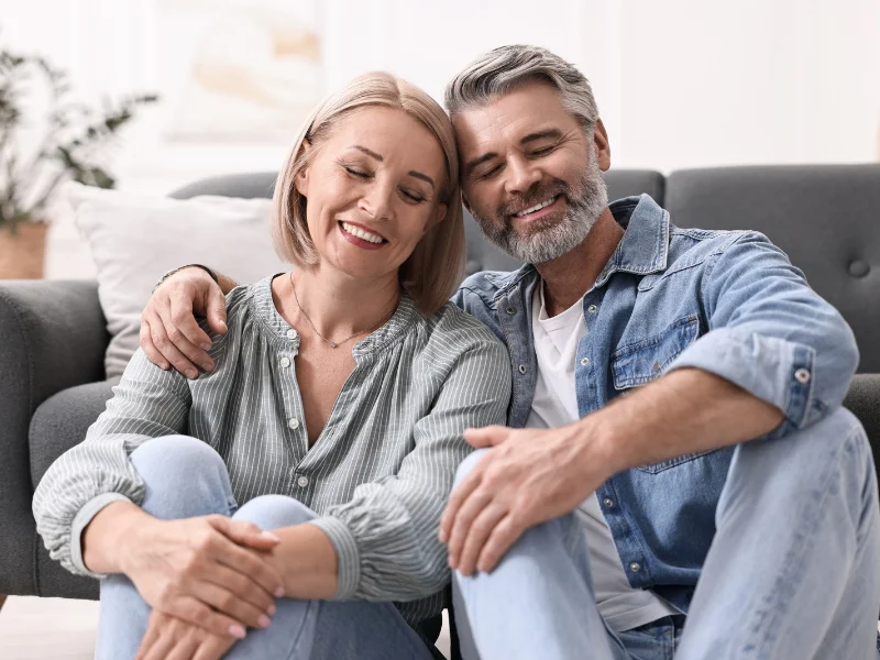Pareja de mediana edad sonriendo junta en su casa de forma tranquila