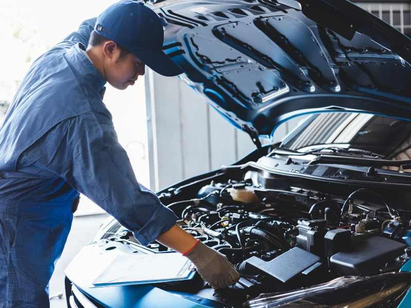 Mecánico realizando labores de mantenimiento y revisión en el motor de un vehículo en un taller