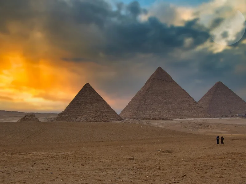 Vista panorámica de las grandes pirámides de Guiza bajo el sol con el desierto egipcio de fondo