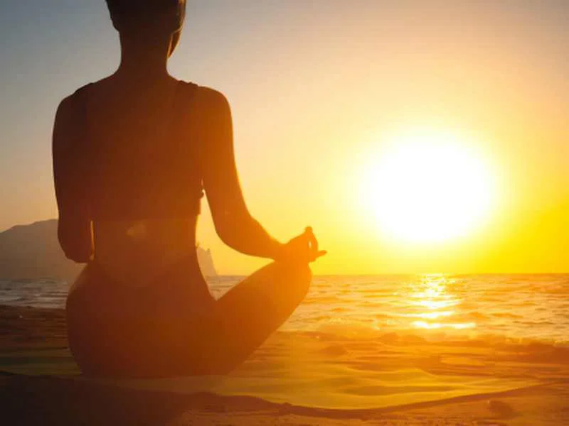 Silueta de una persona en calma practicando meditación al atardecer frente al mar