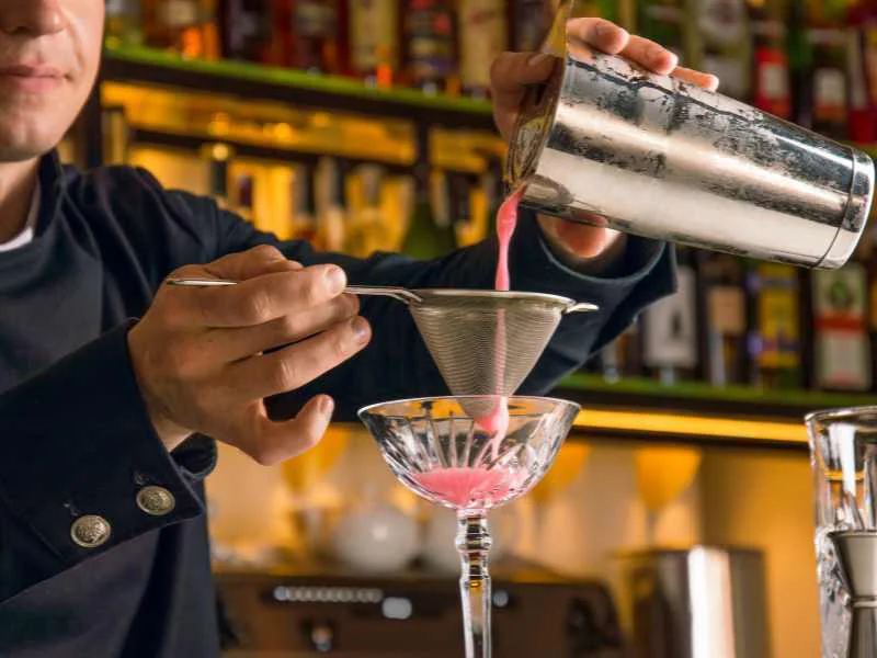 Bartender preparando un cóctel de autor en la barra de una coctelería de referencia