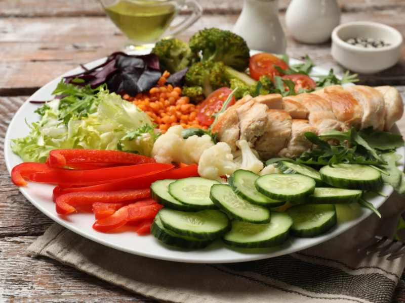 Plato equilibrado con vegetales variados, proteínas magras y grasas saludables sobre una mesa