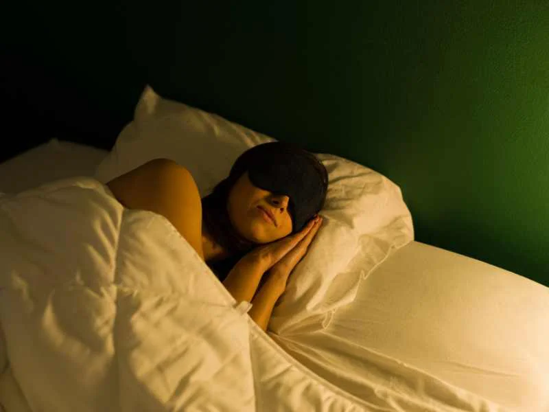Persona relajada en la cama descansando en una habitación a media luz y en silencio