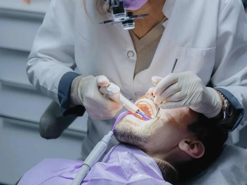 Profesional de la odontología realizando una revisión dental preventiva a un paciente en una clínica