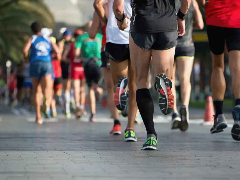Grupo de corredores populares participando en una carrera de asfalto durante la temporada de otoño