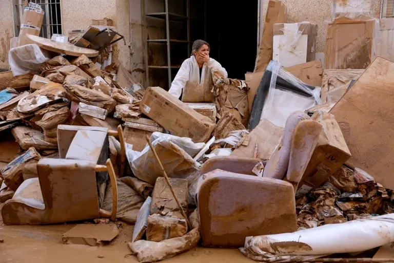 Una mujer observa sus muebles y pertenencias en una calle en Paiporta. EFE/Jorge Zapata