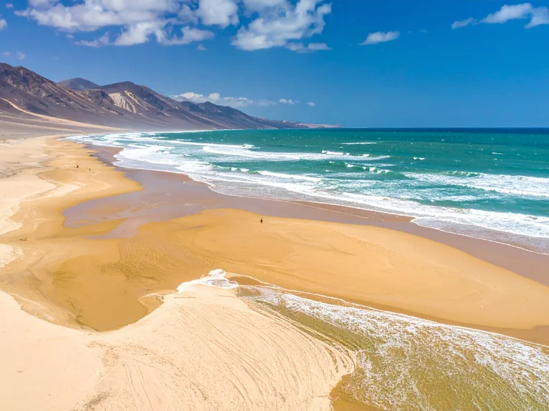 Playa de Cofete en Fuerteventura con arena dorada y montañas al fondo