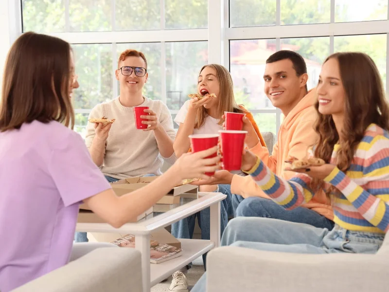 grupo-de-amigos-sentados-en-el-salon-de-una-casa-compartiendo-bebidas