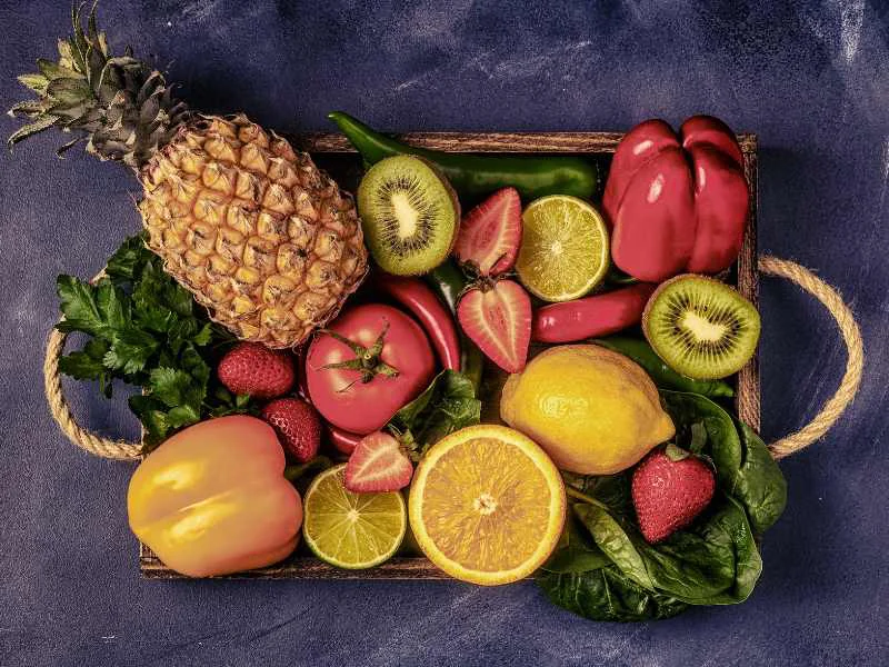 Selección de frutas y verduras frescas ricas en vitamina C como naranjas, fresas, kiwis y pimientos