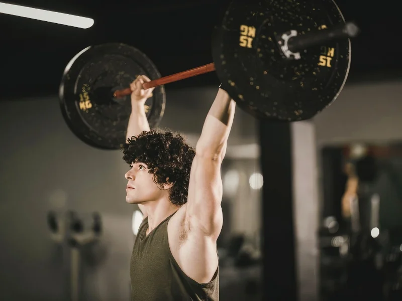 atleta-levantando-una-barra-olimpica-por-encima-de-la-cabeza-en-el-gimnasio