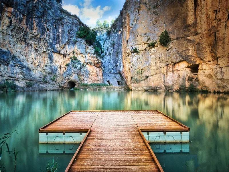 pasarela-de-madera-del-charco-azul-rodeada-de-paredes-de-roca-en-chulilla