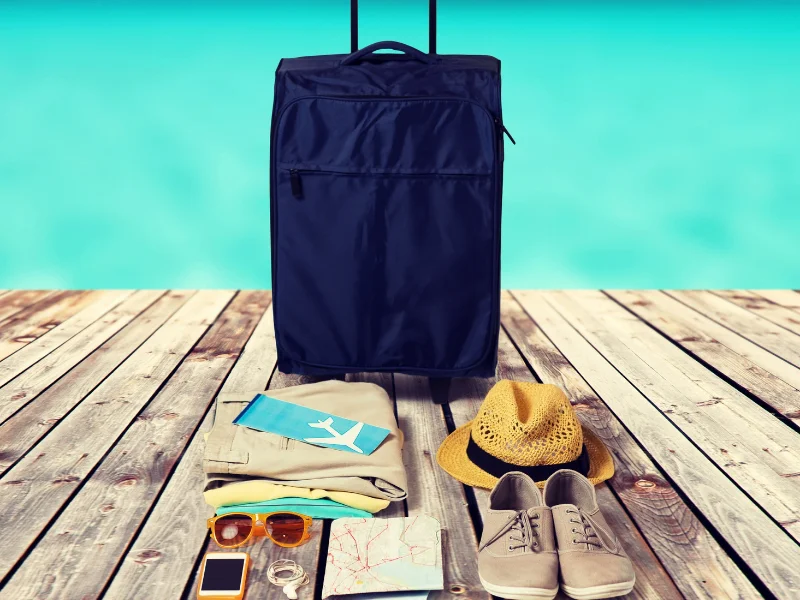 maleta-de-viaje-junto-a-gafas-de-sol-y-mapa-turistico-sobre-un-fondo-playero