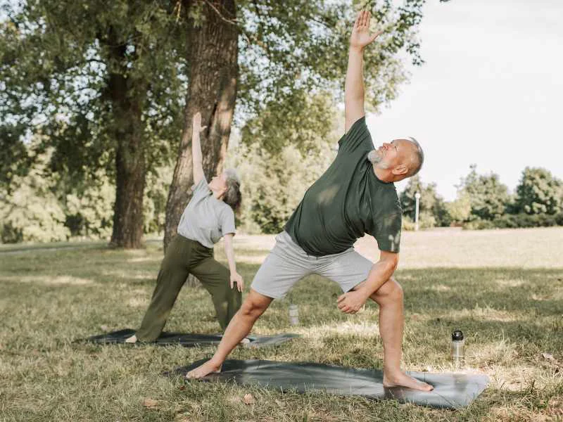 Personas mayores realizando una sesión guiada de estiramientos y yoga al aire libre