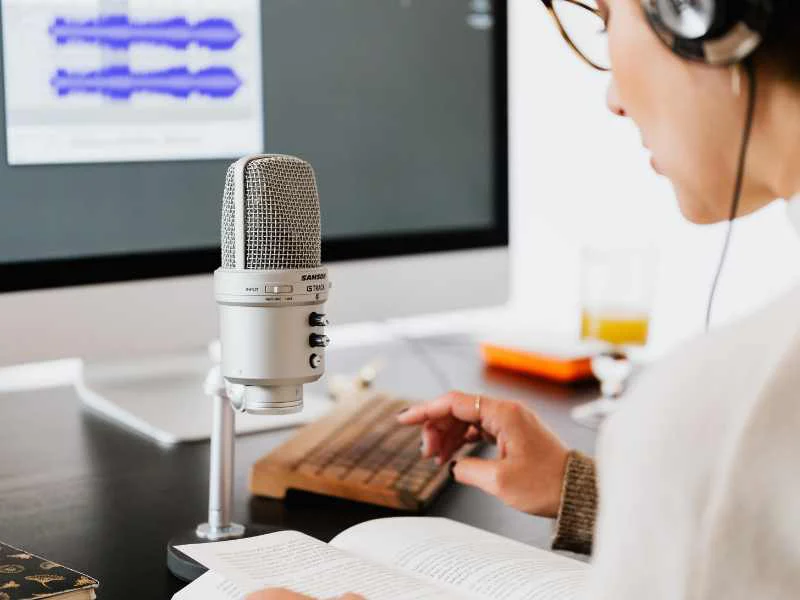 Una persona grabando un episodio de podcast con micrófono profesional frente a una pantalla
