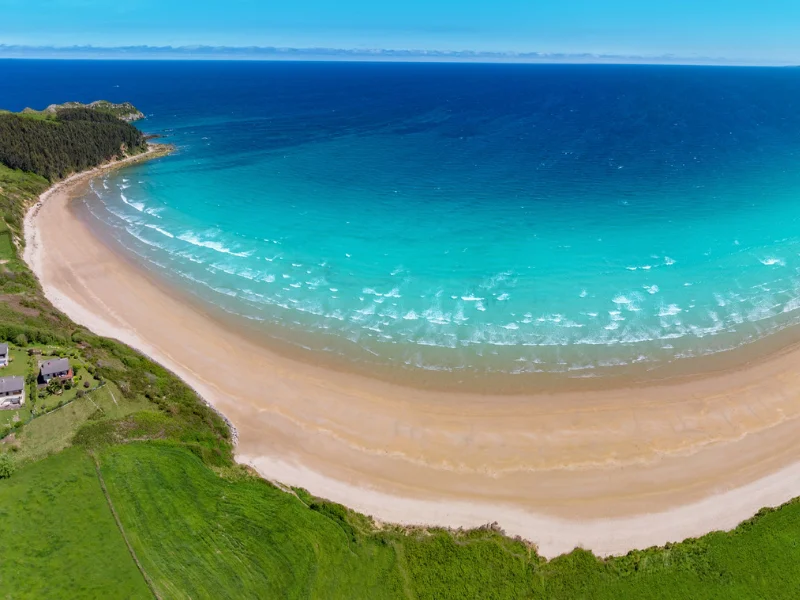 Vista panorámica de la playa de Oyambre con dunas de arena dorada y el mar en Cantabria