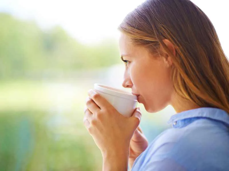 Persona disfrutando de un momento de calma al aire libre sosteniendo una taza de té
